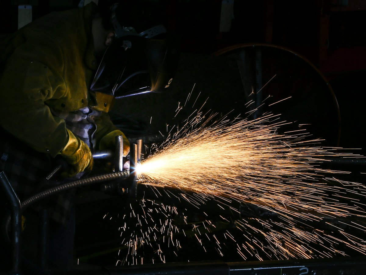 Worker cutting metal with a torch, throwing a wide fan of sparks