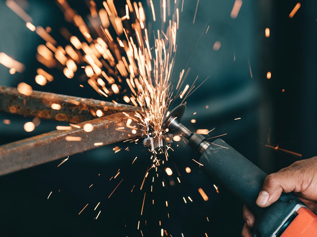 Angle grinder throwing sparks off a rusted steel bar